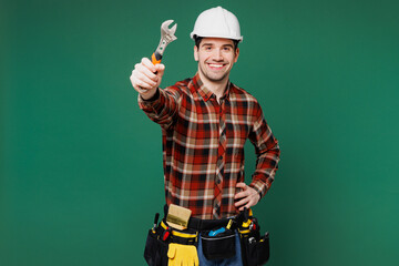 Young employee handyman man wear red shirt hardhat hat work hold show adjustable wrench isolated on...