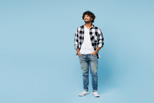 Full body smiling happy cheerful young Indian man he wears shirt white t-shirt casual clothes look aside on area isolated on plain pastel light blue cyan background studio portrait. Lifestyle concept.