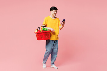 Full body young man wears yellow t-shirt casual clothes shopping hold in hand basket with food...