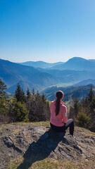 Hiker woman sitting on alpine meadow with scenic view of mountain peaks Carnic andd Julian Alps....