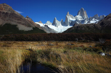 Nature of Patagonia, Towering peaks of mount Fitz Roy and bog overgrown with grass under blue sky...