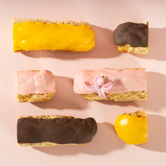 Eclairs set with custard and colorful icing on a pink background pattern. Eclairs with cream filling covered with melted glaze. Traditional French pastry for breakfast. Top view. cafe menu