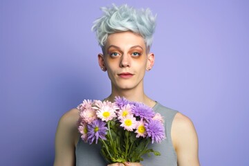 A young transgender person confidently wearing bunny ears and holding a bouquet of spring flowers, set against a solid pastel lilac background with copy space for Easter promotions