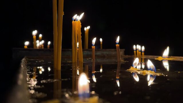 A row of candles casting reflections on a shiny surface, creating a peaceful and meditative ambiance. 