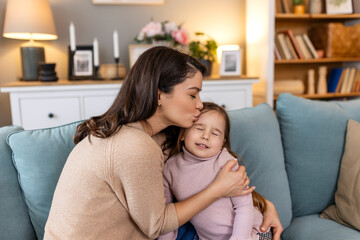 Beautiful young woman and her charming little daughter are hugging and kissing. Beautiful Cute Girl Hugging Her Smiling Mother While She Is Holding Her. Love, happy family