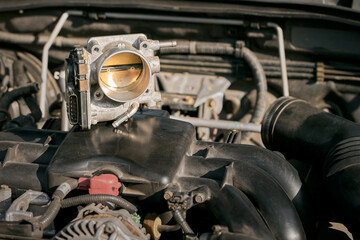 The electronic throttle body and modern car underhood with opposed engine in the background. Engine maintenance. Industrial technology.