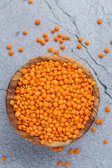 Photo of red lentils in wooden bowl with wooden measuring cup on wooden background.  Healthy lifestyle. Vegetarian and vegan diet.