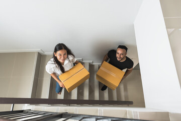 Young couples holding boxes going upstairs on moving house