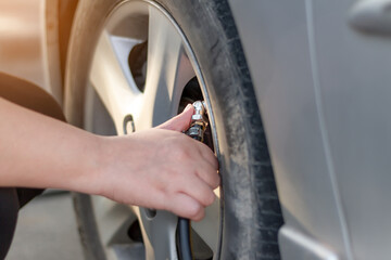 Woman's hand putting air into a car wheel