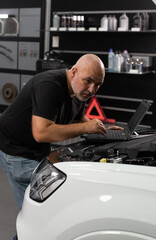 Car Service Manager or Mechanic Uses a Tablet Computer with a Futuristic Interactive Diagnostics Software. Specialist Inspecting the Vehicle in Order to Find Broken Components In the Engine Bay