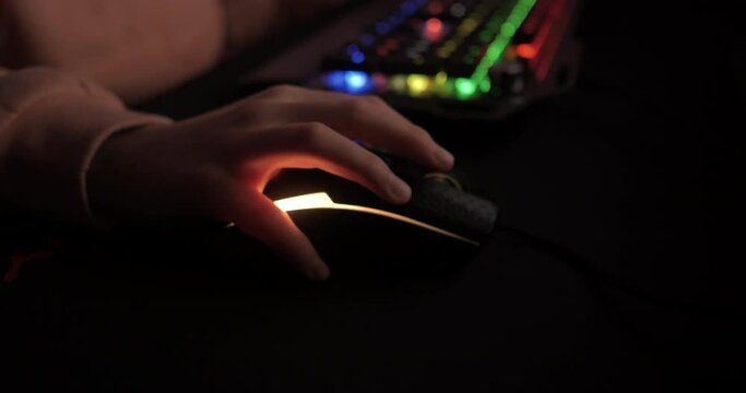 RGB Mouse. Close up Hand of Gamer Girl, Moving Mouse While Playing PC Game. Person Plays Computer Video Game in Dark Room, Cybersport Gaming, Children Gaming Addiction. Video Game Live Streaming.