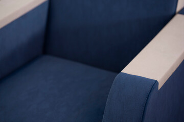 Close-up of an upholstered armchair made of a combined blue and beige fabric. A piece of...