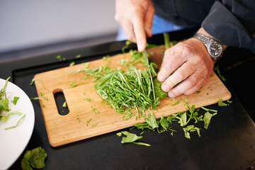 Hands, salad and chopping board with a man and green leaves for cooking health food in a home....