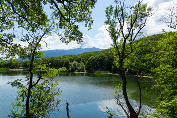 Fototapeta na wymiar Mountains surround the mountain lake. The surface of the lake reflects sunlight. Landscape