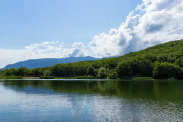 Fototapeta na wymiar Mountains surround the mountain lake. The surface of the lake reflects sunlight. Landscape