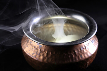 Brass copper metal style pot cauldron smoke vape fog lit inside rising flowing moving rotate on black background - 742451942