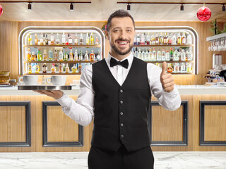 Waiter holding a tray with coffee cups and showing thumbs up at a bar