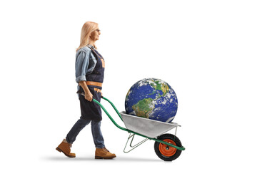 Full length profile shot of a woman pushing a wheelbarrow with the planet earth inside
