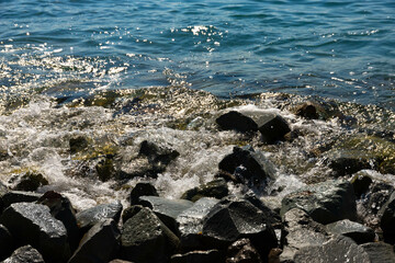 Large black stones on the Black Sea coast with waves crashing against them. Landscape