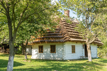 Stary drewniany budynek z dachem pokrytym strzechą budowany na dawnej polskiej wsi