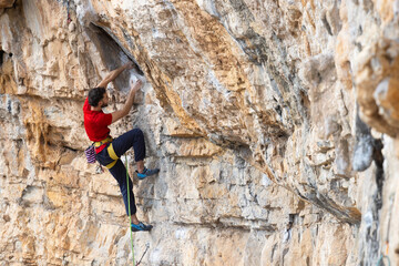 Man in red t-shirt scalded on gray wall, playing sports, reaching limit