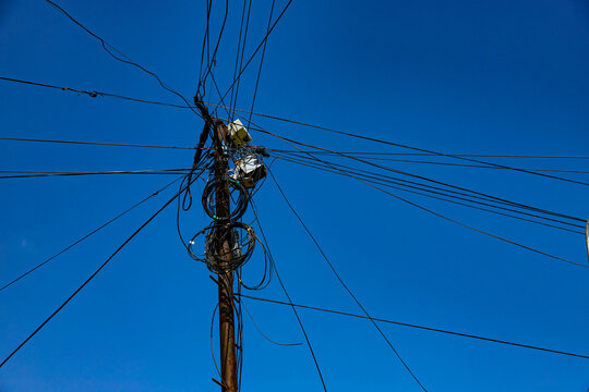Street pole with many electrical wires and fiber optic cables, Fiber-optic cable against the blue sky.