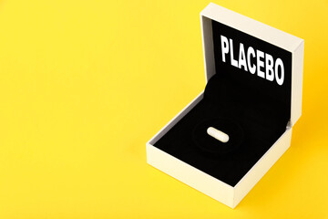 Placebo, the text is written on a gift box, a gift with one white capsule, on a yellow background. Copy space