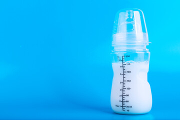 Baby feeding bottle with pacifier on blue background. Copy space.
