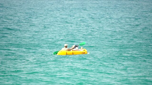 Aerial view of a family kayaking in calm blue sea. Unrecognizable woman and man. Packraft light raft used for expedition or adventure racing inflatable boat at sea. Summer holiday and travel concept