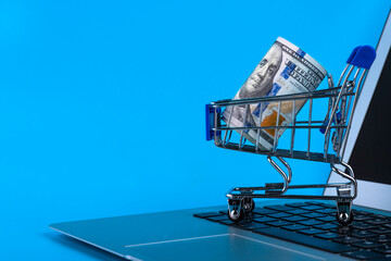 Shopping cart and computer mouse, roll one hundred dollar bills online shopping concept. Copy space.
