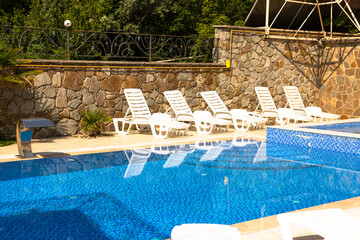 Pool with blue water ladder for descent and ascent into the water. The sun loungers are empty by...