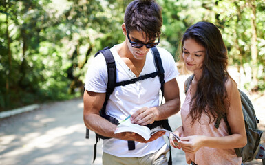 Couple, map and search for hiking in forest with reading for thinking, holiday and ideas on path....