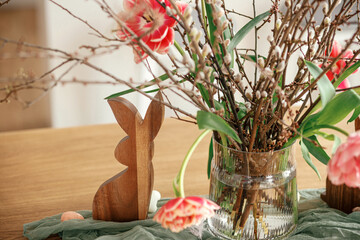 Stylish easter decoration on wooden table close up in room. Beautiful tulips bouquet with willow...