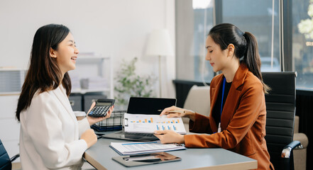 Businesswoman leading team meeting and using tablet and laptop computer with financial in co working office