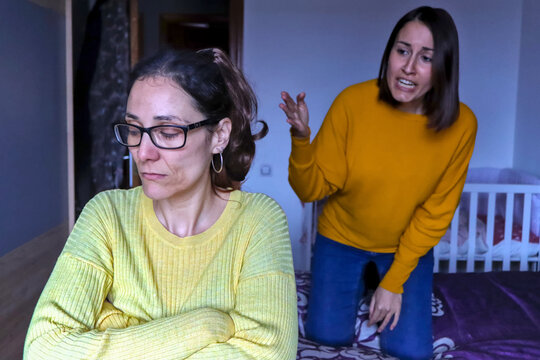 Caucasian lesbian couple arguing in their room, one of them reproaching things to the other sad woman, with a somewhat dark atmosphere. LGBT couple discussion concept