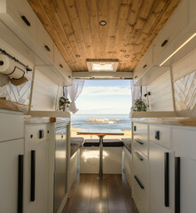 Interior of a cozy camper with Nordic design in front of a beach landscape.
Lifestyle, travel, tourism, outdoors