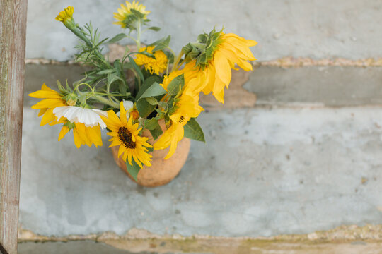 Overhead view of sunflowers and cosmos flowers in a vase on steps
