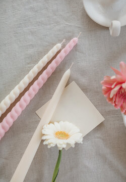 Overhead view of assorted candles, blank paper card and gerbera flowers on a table