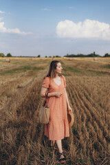 A young girl in a long dress and long hair, holding a wicker bag. A girl walks around a crooked...