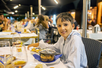 Cute child, boy, eating fish for dinner in a restaurant in Portugal