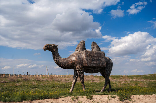 metal sculpture of a camel outdoors against a blue sky background.