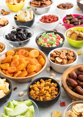 Mix of healthy dried sweet fruits and berries in various bowl plates on light kitchen background.Macro.