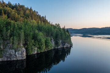Wald auf Felsen am See bei Sonnenaufgang