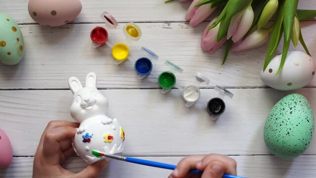child coloring the Easter bunny , wooden table with tulips and eggs