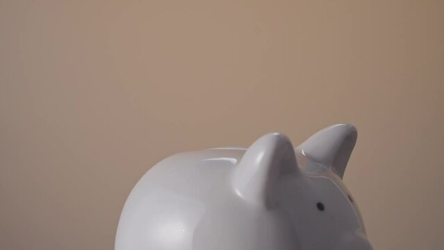 Dropping quarter into piggy savings bank close-up