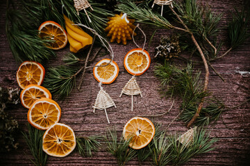 Obraz na płótnie Canvas Christmas decoration, bees wax candle, dried orange slices and handmade Christmas tree ornament on wooden background