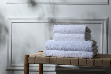Stacked terry towels on wicker bench indoors, space for text