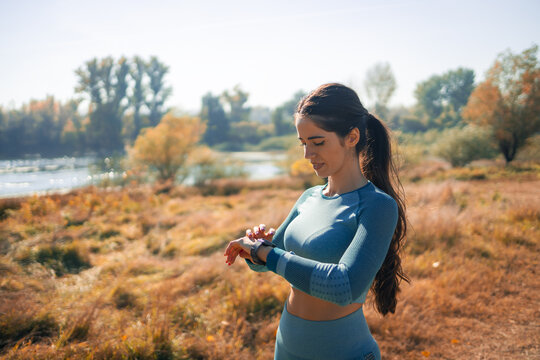 An athletic young woman checking a smart watch after a jog in nature