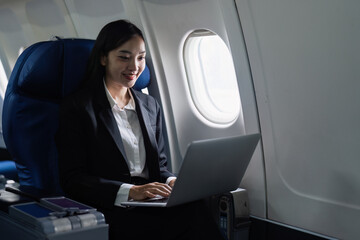 Beautiful Asian businesswoman working with laptop in aeroplane. working, travel, business concept