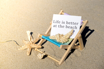 LIFE IS BETTER AT THE BEACH text on paper greeting card on background of beach chair lounge...